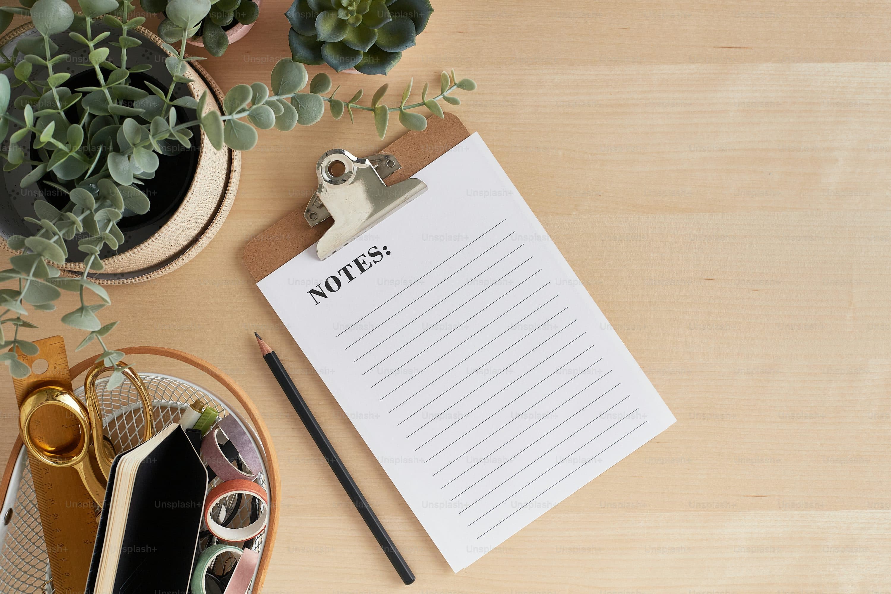 a notepad sitting on top of a wooden table next to a plant